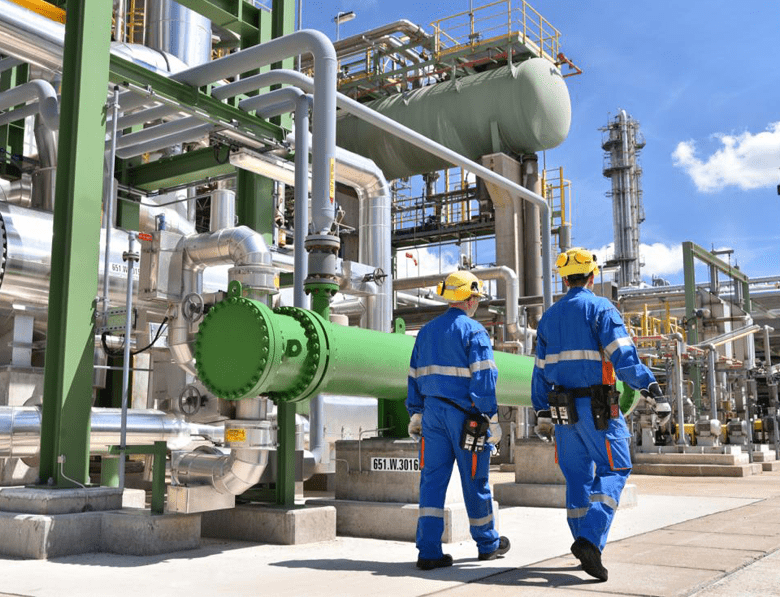 Chemical industry plant - workers in work clothes in a refinery with pipes and machinery
