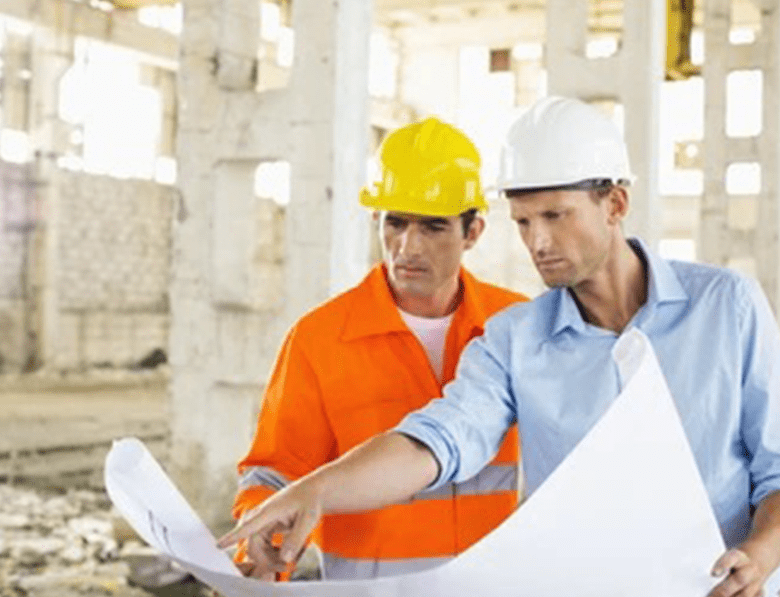 Male architects discussing over blueprint at construction site